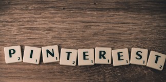 Las fichas de Scrabble deletrean "PINTEREST" en una superficie de madera, resaltando el impacto de la plataforma en el marketing online.