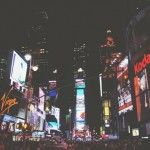 Times Square de noche, repleta de gente e iluminada por carteles y anuncios brillantes.