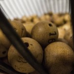 Bolas de bingo de madera en una jaula de metal, listas para jugar.