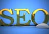 Las letras 3D doradas "SEO" se destacan orgullosamente sobre un fondo azul, con un mouse de computadora conectado por un cable en el frente, simbolizando la importancia del contenido y las estrategias para un posicionamiento efectivo.