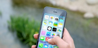Una mano sostiene un teléfono inteligente que muestra varios íconos de aplicaciones, haciendo alusión al vasto mercado de tecnologías digitales, frente a un fondo exterior borroso.