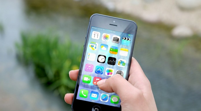 Una mano sostiene un teléfono inteligente que muestra varios íconos de aplicaciones, haciendo alusión al vasto mercado de tecnologías digitales, frente a un fondo exterior borroso.