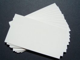 Una pila de tarjetas de presentación blancas en blanco, perfectas para la marca, se extiende sobre una superficie oscura.
