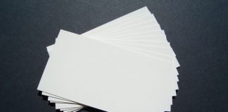 Una pila de tarjetas de presentación blancas en blanco, perfectas para la marca, se extiende sobre una superficie oscura.