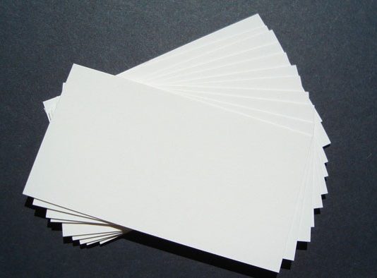 Una pila de tarjetas de presentación blancas en blanco, perfectas para la marca, se extiende sobre una superficie oscura.