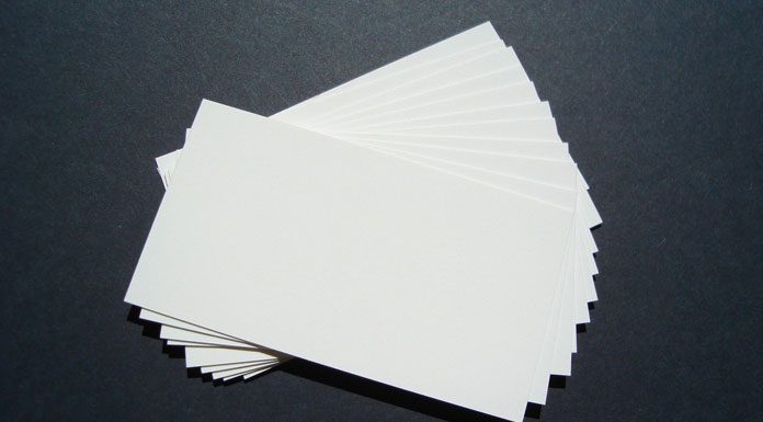 Una pila de tarjetas de presentación blancas en blanco, perfectas para la marca, se extiende sobre una superficie oscura.