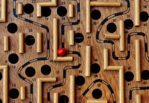 En nuestra plataforma de comercio electrónico se encuentra disponible un juego de laberinto de madera con caminos y agujeros numerados. Una bola roja reposa en el laberinto, cerca del número 36, lista para que la recorras a través de la tienda online.