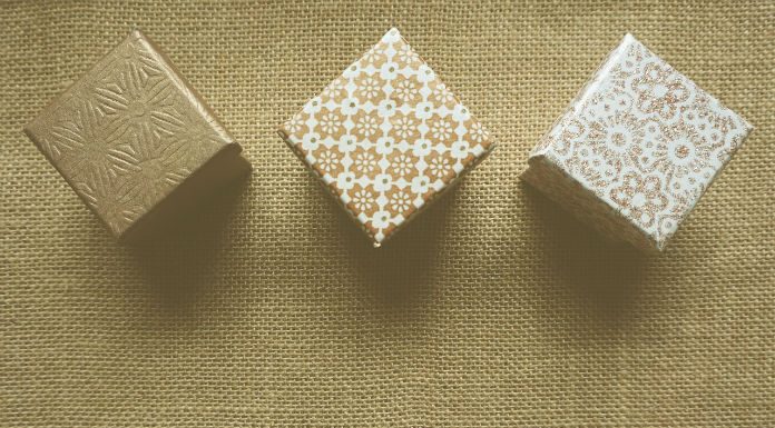 Regalo promocional Tres cajas de regalo con patrones texturizados están dispuestas en fila sobre una superficie de arpillera, listas para deleitar a sus clientes.