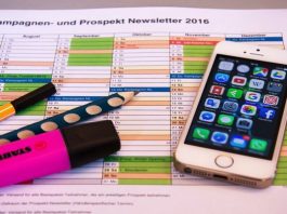 Un calendario con secciones de colores, un teléfono inteligente que muestra aplicaciones de marketing digital, un resaltador rosa, un marcador negro y un bolígrafo con lunares azules se encuentran sobre el escritorio de una empresa innovadora.