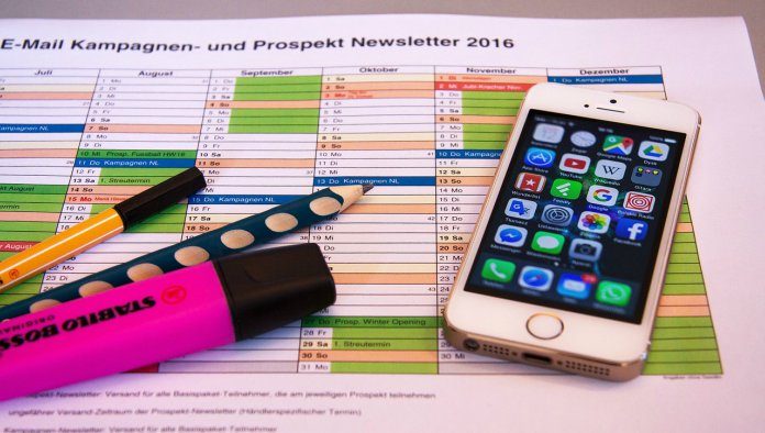 appsUtiles Un calendario con secciones de colores, un teléfono inteligente que muestra aplicaciones de marketing digital, un resaltador rosa, un marcador negro y un bolígrafo con lunares azules se encuentran sobre el escritorio de una empresa innovadora.