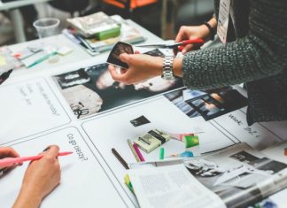 La relevancia del buen diseño de logos Personas colaborando en una mesa llena de papeles, fotos, marcadores y revistas, intercambiando ideas para un nuevo logotipo de empresa que se destaque de la competencia.