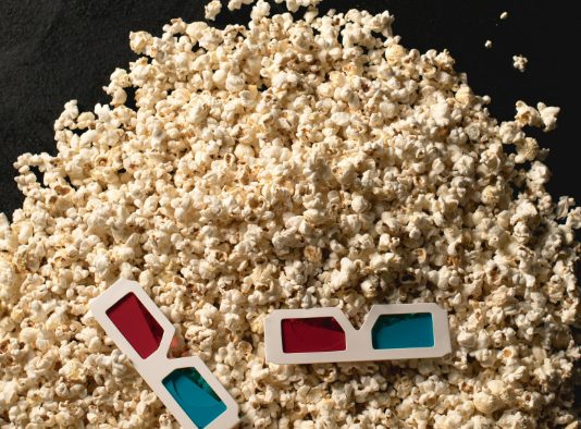 Una pila de palomitas de maíz con un par de gafas 3D rojas y azules encima te invita a adentrarte en un mundo donde las animaciones 3D cobran vida.