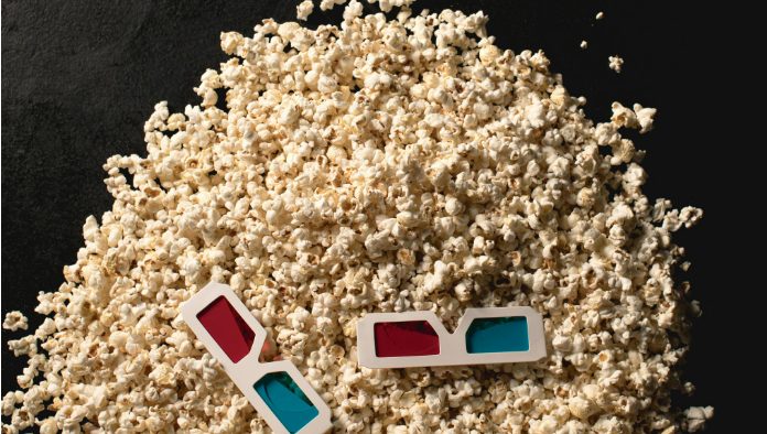 Una pila de palomitas de maíz con un par de gafas 3D rojas y azules encima te invita a adentrarte en un mundo donde las animaciones 3D cobran vida.