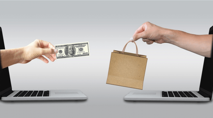 La captación de usuarios potenciales a través del marketing promocional Dos pantallas de portátiles con manos que emergen; una sostiene un billete de dólar y la otra una bolsa de la compra. Esta escena captura la esencia de las compras y el marketing online, y simboliza cómo las estrategias de promoción llegan a los clientes sin esfuerzo en la era digital.