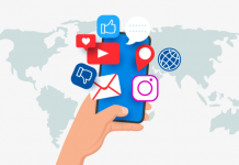 Una mano que sostiene un teléfono inteligente con varios íconos de redes sociales flotando sobre él. De fondo, un mapa del mundo.