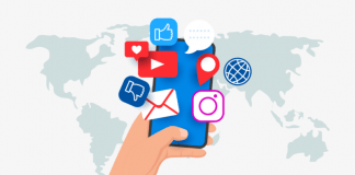 Una mano que sostiene un teléfono inteligente con varios íconos de redes sociales flotando sobre él. De fondo, un mapa del mundo.