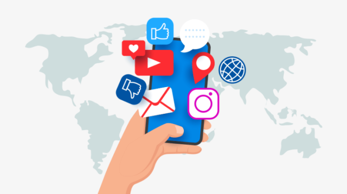 mailrelay-emailmarketing Una mano que sostiene un teléfono inteligente con varios íconos de redes sociales flotando sobre él. De fondo, un mapa del mundo.